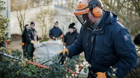  Ein Mitarbeiter im Bereich Gartenbau kürzt eine Hecke.